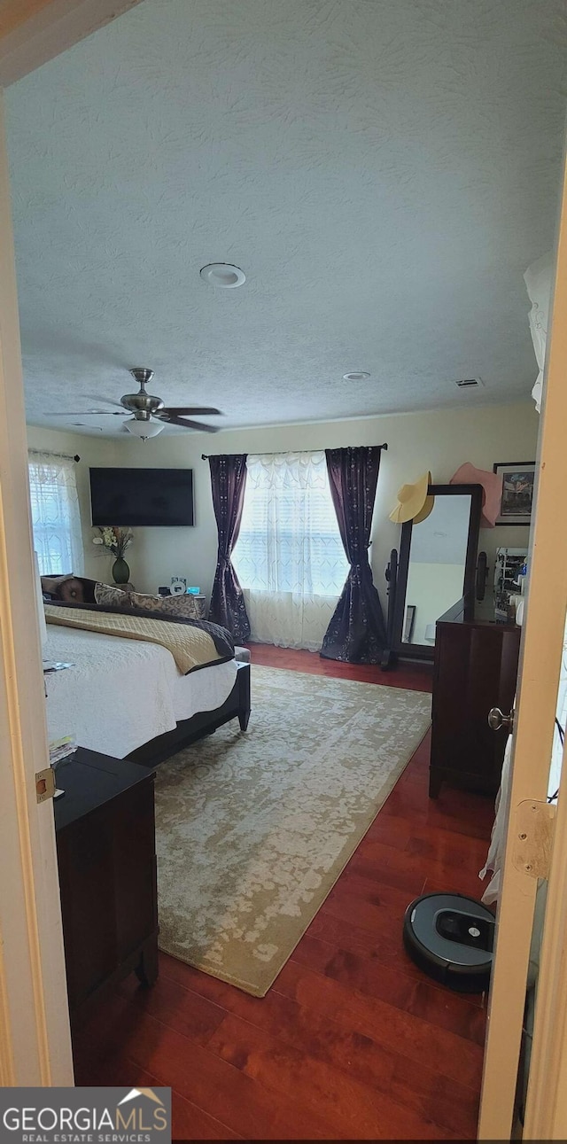 bedroom featuring ceiling fan, a textured ceiling, and dark hardwood / wood-style flooring