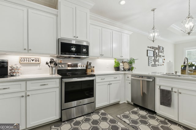 kitchen featuring hanging light fixtures, white cabinets, appliances with stainless steel finishes, and sink