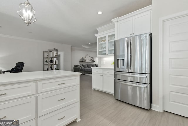 kitchen featuring white cabinetry, stainless steel fridge with ice dispenser, crown molding, and hanging light fixtures