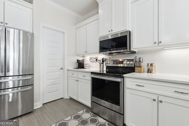 kitchen with light hardwood / wood-style floors, appliances with stainless steel finishes, tasteful backsplash, crown molding, and white cabinets