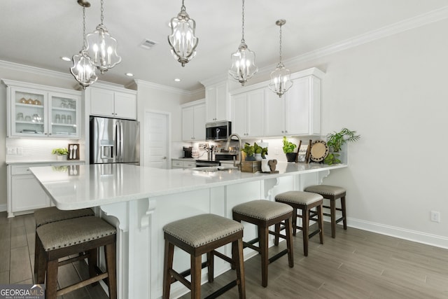 kitchen featuring decorative light fixtures, white cabinetry, and stainless steel appliances