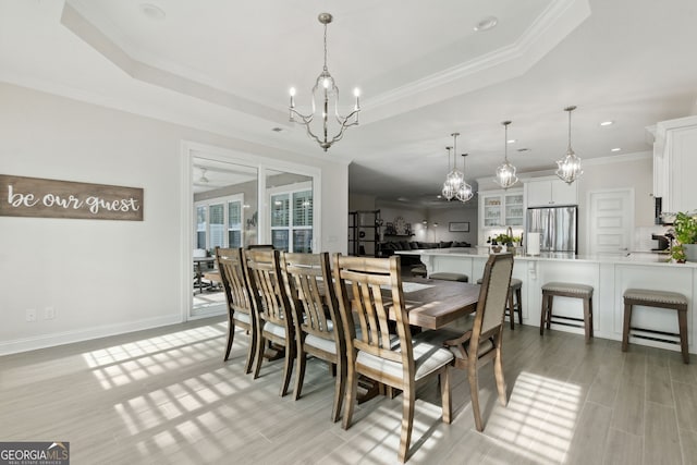 dining space featuring crown molding, ceiling fan with notable chandelier, and a tray ceiling