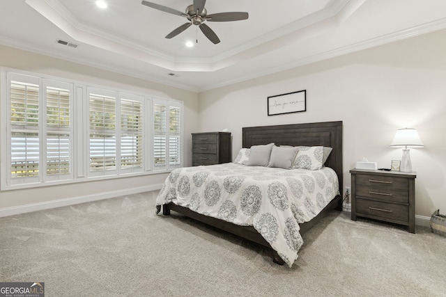 carpeted bedroom with ceiling fan, crown molding, and a tray ceiling