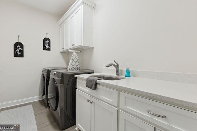 laundry area with washer and dryer, cabinets, sink, and light wood-type flooring