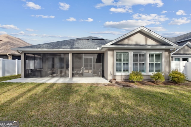 rear view of house featuring a sunroom and a lawn