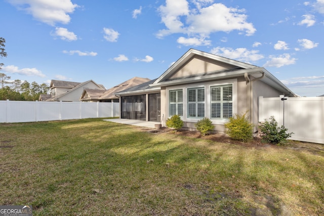 rear view of property with a patio, a yard, and a sunroom