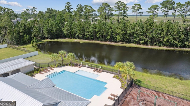 view of swimming pool featuring a water view, a lawn, and a patio area