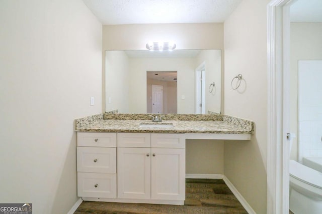 bathroom with hardwood / wood-style flooring, a textured ceiling, toilet, and vanity