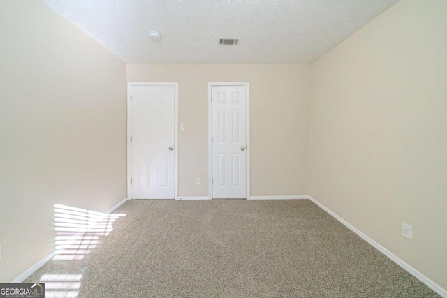 spare room with a textured ceiling and carpet flooring