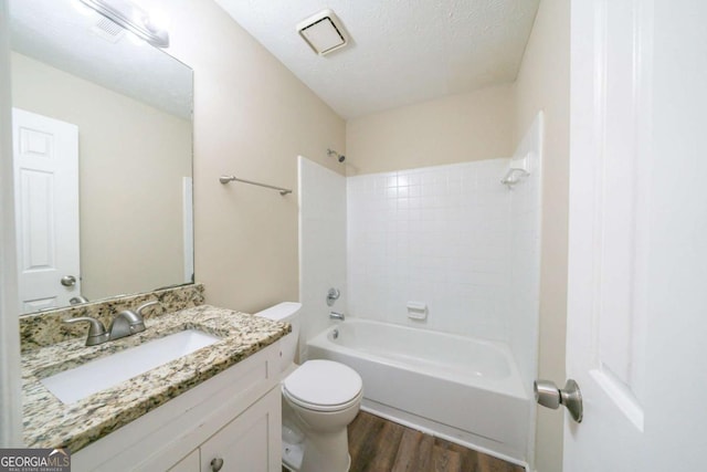 full bathroom with toilet, hardwood / wood-style floors, a textured ceiling, tub / shower combination, and vanity