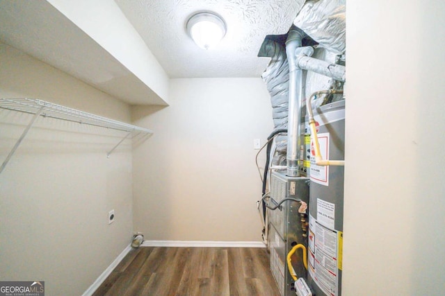 clothes washing area with water heater, dark hardwood / wood-style floors, hookup for an electric dryer, and a textured ceiling