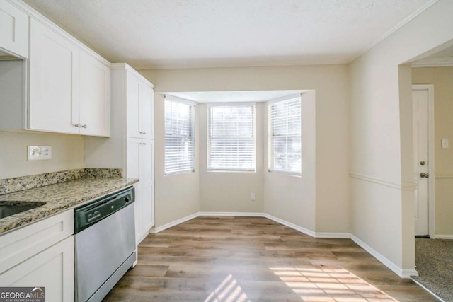 kitchen with light wood-type flooring, light stone countertops, a textured ceiling, stainless steel dishwasher, and white cabinets