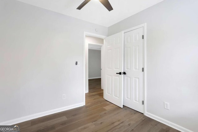 unfurnished bedroom with ceiling fan, a closet, and hardwood / wood-style flooring