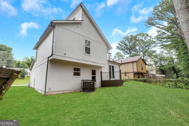 rear view of property featuring cooling unit and a yard