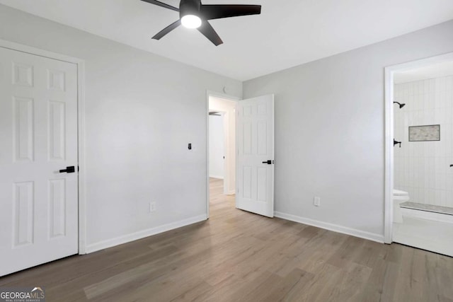 unfurnished bedroom with ceiling fan, wood-type flooring, and ensuite bath