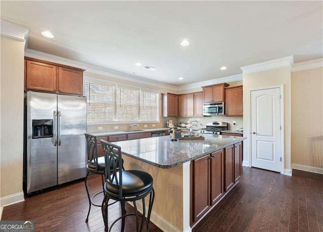 kitchen featuring dark stone countertops, a center island, dark wood-type flooring, ornamental molding, and stainless steel appliances