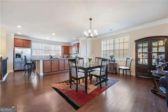 dining room featuring dark hardwood / wood-style floors, crown molding, and an inviting chandelier