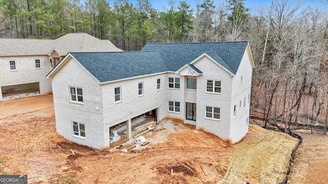 view of front of home with brick siding and roof with shingles