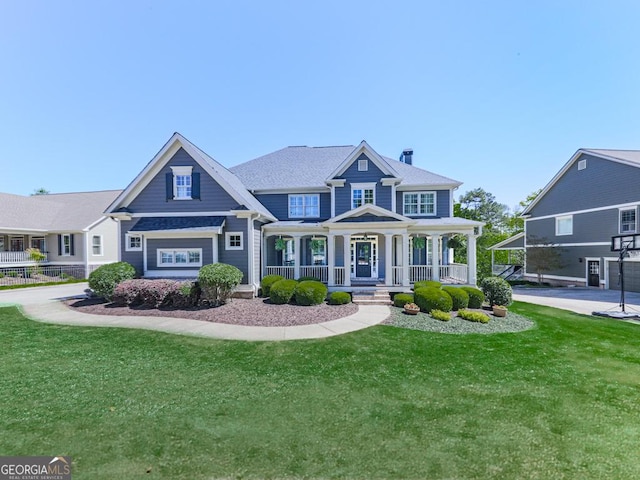 craftsman-style home featuring a chimney, a front yard, and covered porch