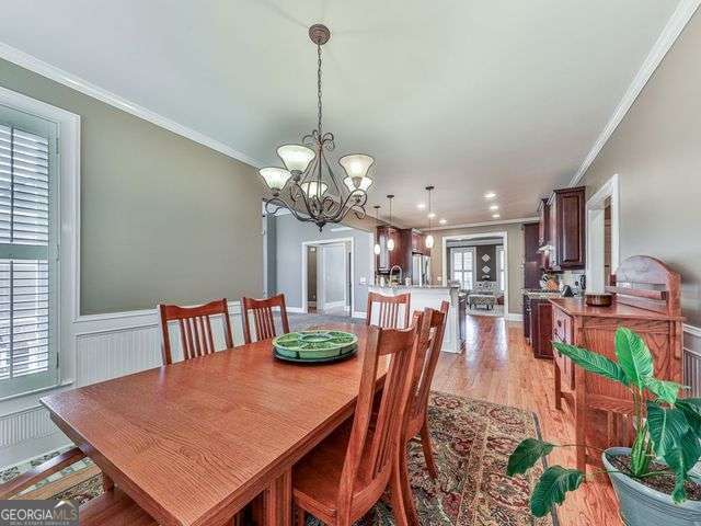 dining space featuring light wood-type flooring and crown molding