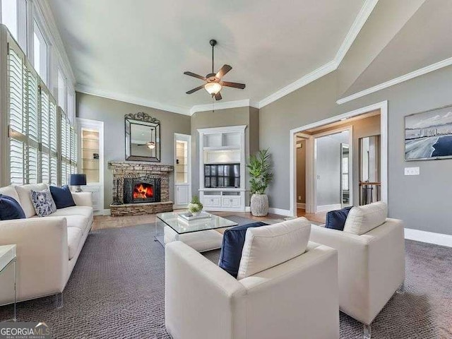 living room with ceiling fan, dark colored carpet, built in features, a fireplace, and ornamental molding