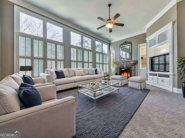 living room with ceiling fan, dark carpet, ornamental molding, and a fireplace