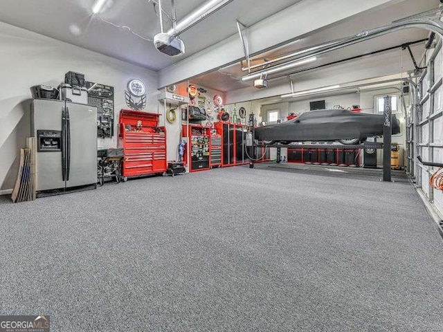 garage featuring stainless steel refrigerator with ice dispenser, a workshop area, and a garage door opener