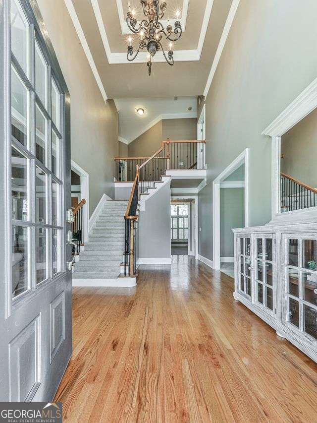 entrance foyer featuring wood-type flooring, ornamental molding, and a towering ceiling