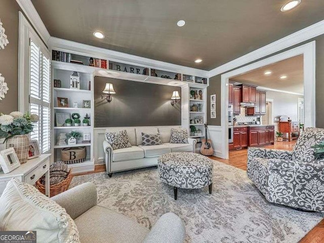 living room featuring built in shelves, ornamental molding, and light hardwood / wood-style floors