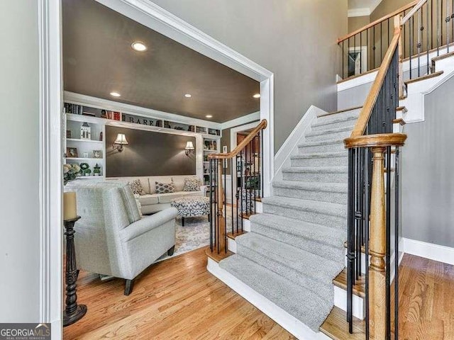 stairs featuring recessed lighting, wood finished floors, crown molding, and baseboards