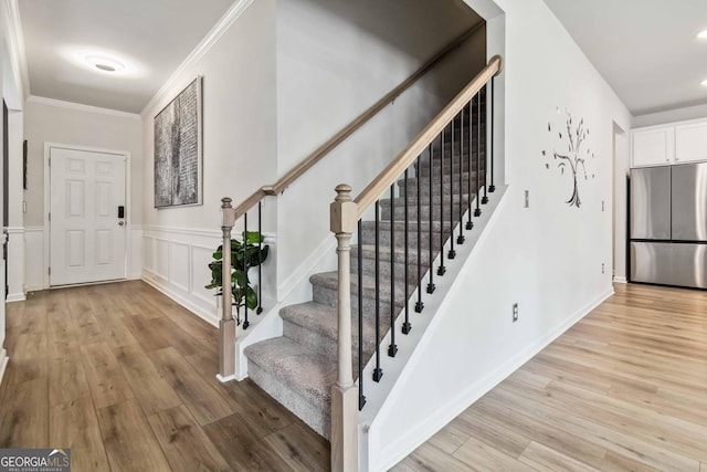 foyer with crown molding and light hardwood / wood-style floors