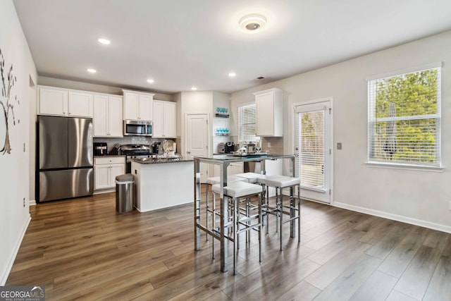 kitchen featuring stainless steel appliances, a center island, white cabinets, and dark hardwood / wood-style flooring