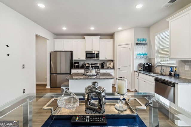 kitchen with a kitchen island, sink, white cabinets, dark stone counters, and stainless steel appliances