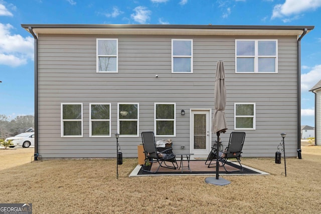 back of property with a lawn and a patio area