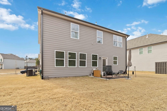 rear view of property featuring cooling unit, a yard, and a patio area