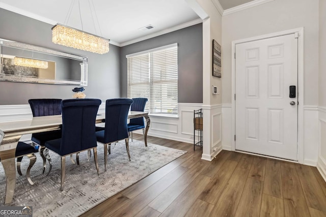 dining room with crown molding, a chandelier, and hardwood / wood-style flooring