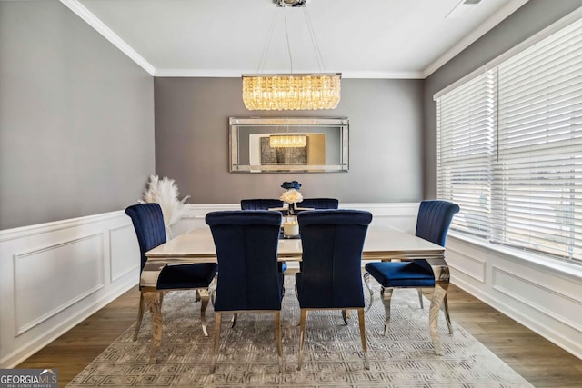 dining space featuring hardwood / wood-style flooring, ornamental molding, a healthy amount of sunlight, and a notable chandelier