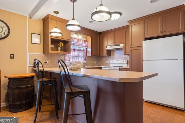 kitchen with a breakfast bar, kitchen peninsula, crown molding, white appliances, and light wood-type flooring