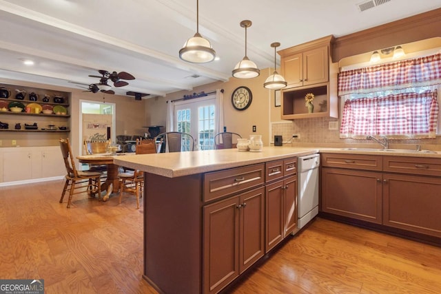 kitchen featuring decorative light fixtures, backsplash, dishwasher, sink, and light wood-type flooring