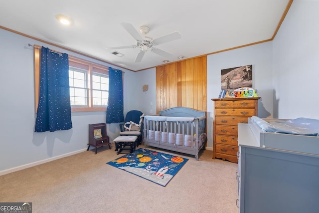 bedroom with ceiling fan, crown molding, light colored carpet, and a crib