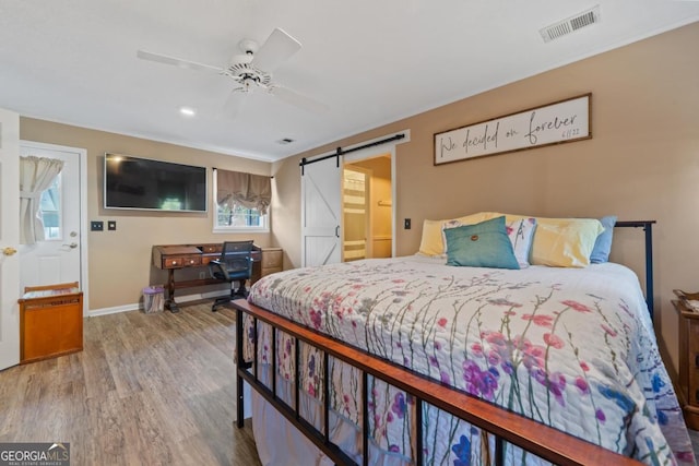 bedroom featuring ceiling fan, wood-type flooring, and a barn door