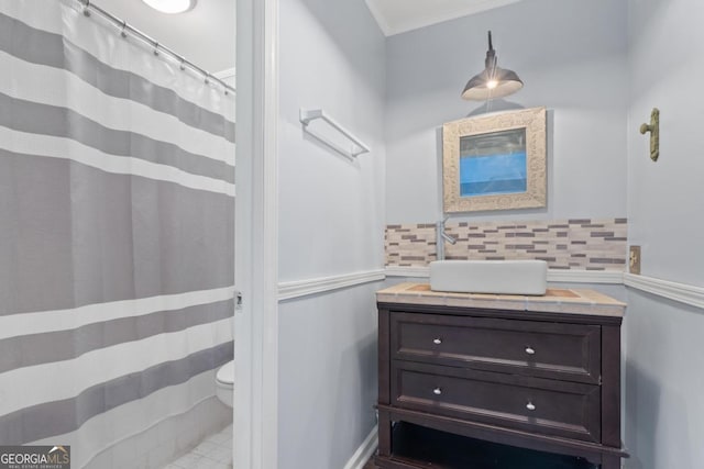 bathroom featuring sink, backsplash, toilet, and ornamental molding