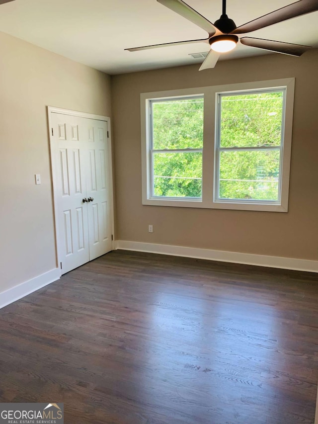 empty room with dark wood-type flooring and ceiling fan