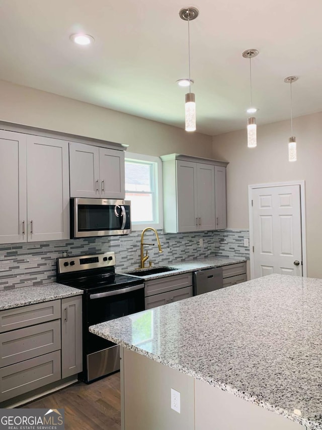 kitchen with light stone counters, hanging light fixtures, gray cabinets, and stainless steel appliances