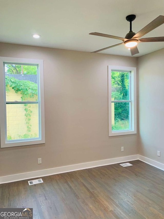 unfurnished room featuring ceiling fan, a healthy amount of sunlight, and dark wood-type flooring