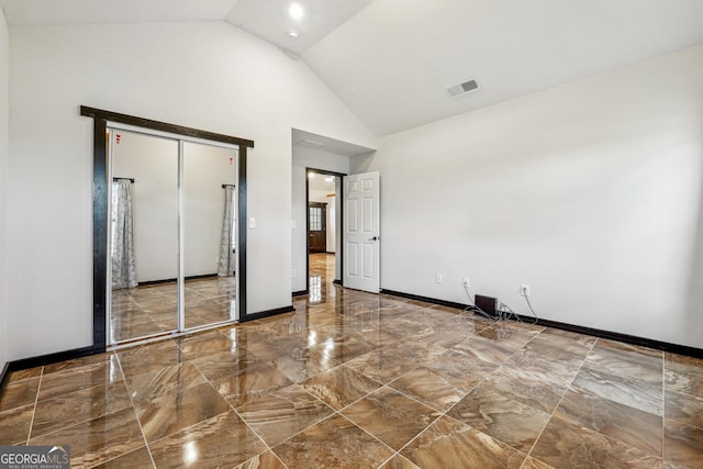 unfurnished bedroom featuring high vaulted ceiling and a closet