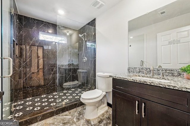 bathroom with toilet, vanity, and a shower with shower door