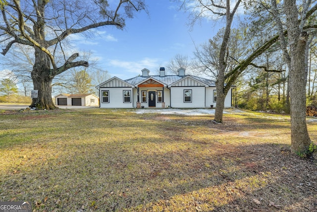 view of front of home featuring a front lawn, a garage, and an outdoor structure