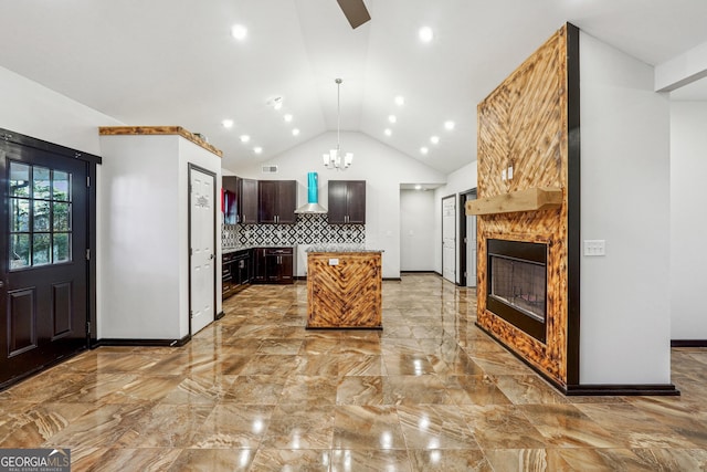 kitchen featuring dark brown cabinetry, lofted ceiling, wall chimney exhaust hood, a kitchen island, and decorative backsplash