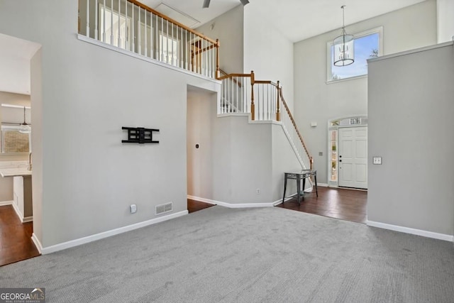interior space with visible vents, a towering ceiling, baseboards, stairway, and carpet